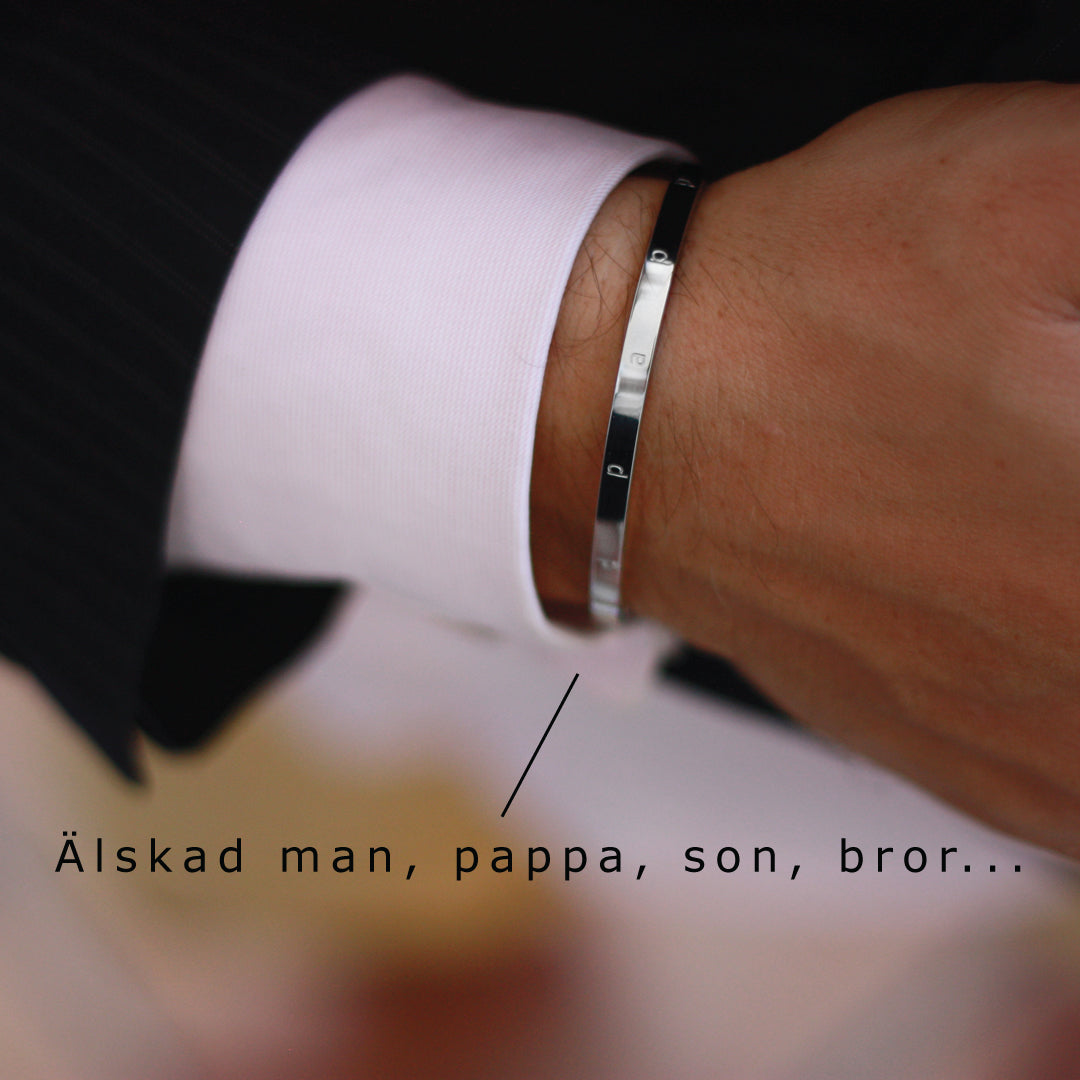 Smalt stilrent armband i blank stål med text graverat på ovansidan